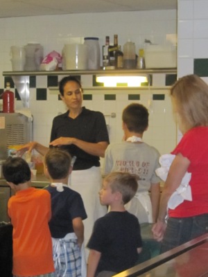 Aquarelle owner Terry Wilson gives children a tour of the kitchen before teaching them how to cook at a birthday party.
